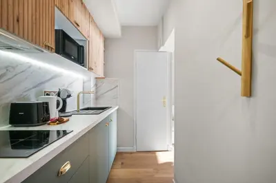 a kitchen with white cabinets and a refrigerator at Vue mer panoramique - Cocon cosy et luxe - Clim et Wifi in Cagnes-sur-Mer