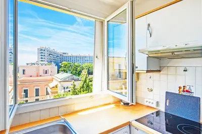 a kitchen with a window with a view of the city at Espace Anahit 2 piece meublé avec balcon, proche Tram Magnan et plages BAIL MOBILITE in Nice