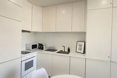 a white kitchen with white cabinets and a microwave at appartement moderne pour 3 pers Hyper Centre proche Jean Médecin in Nice