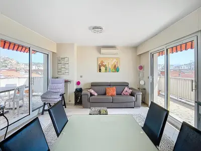 a living room with a table and a couch at Penthouse d'exception avec terrasse panoramique in Nice