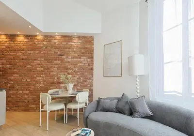 a living room with a couch and a brick wall at Moderne et lumineux en centre-ville - 2 Chambres in Nice