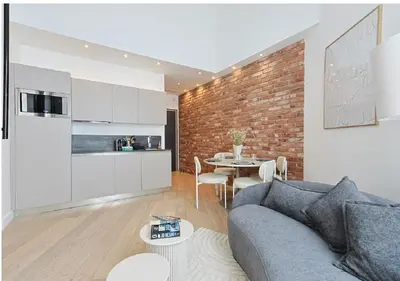 a living room with a couch and a brick wall at Moderne et lumineux en centre-ville - 2 Chambres in Nice