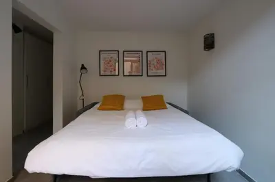 a bedroom with a white bed with two yellow pillows at Nümad Suites in Nice
