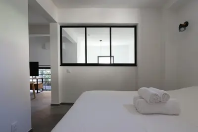 a white bedroom with a bed and a window at Nümad Suites in Nice