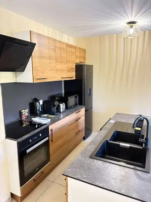a kitchen with a sink and a black refrigerator at Le Ciel de Fabron Piscine et Tennis in Nice