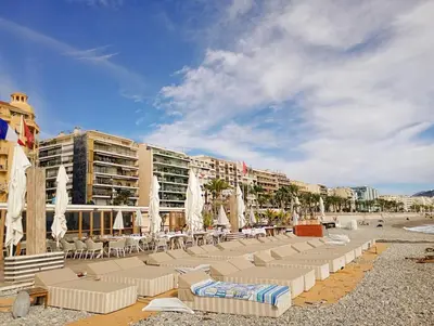 a beach with lounge chairs and umbrellas and buildings at Artemare, il fascino del classico con ogni comfort in Nice