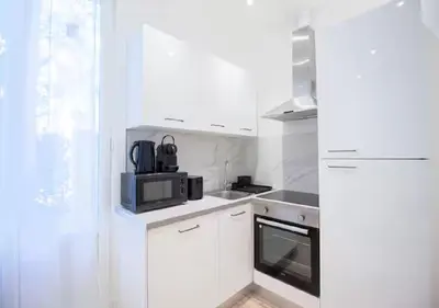a white kitchen with a microwave and a stove at Nid Douillet au Cœur de Nice avec terrasse et clim in Nice