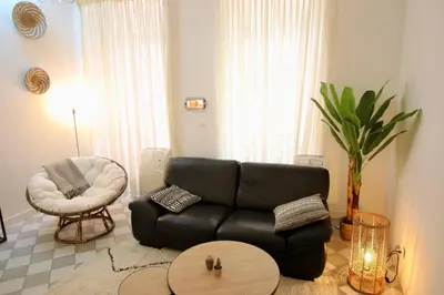 a living room with a black couch and a chair at Charmant appartement au sein de la vieille ville in Villefranche-sur-Mer