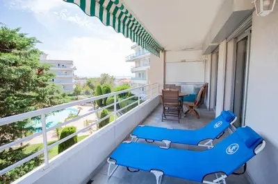 a balcony with two blue chairs and a table at Terrasse, piscine & parking sur la Côte d'Azur in Saint-Laurent-du-Var