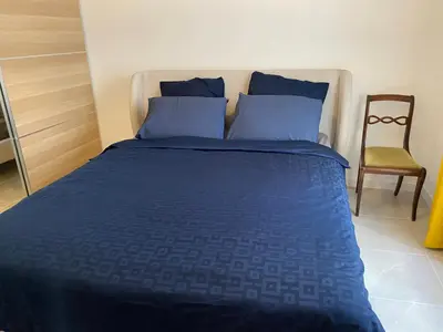 a bed with blue sheets and a chair in a room at Cosy Nice Promenade des Anglais Beach Apartment 2 rooms in Nice