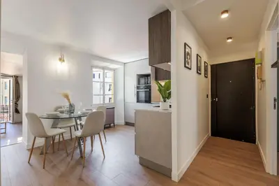 a kitchen with white and wooden cabinets and a table at Bright 3 rooms apartment close to Place Massena in Nice