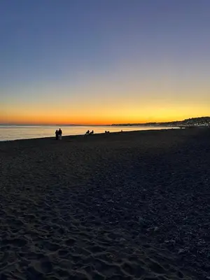 a group of people walking on the beach at sunset at Appartement Neuf Nice Carré Or à 2 pas de la mer tout équipé in Nice