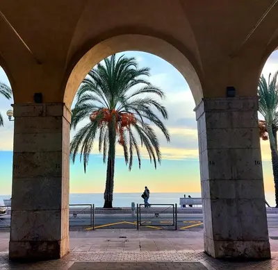 a person standing under an arch with a palm tree at Charmant Duplex Vieux Nice, proche mer, WiFi, Clim in Nice