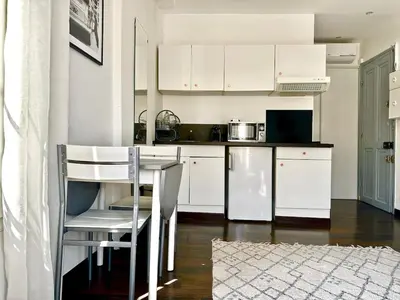 a kitchen with white cabinets and a table and chairs at Studio cosy proche des plages & promenade in Nice