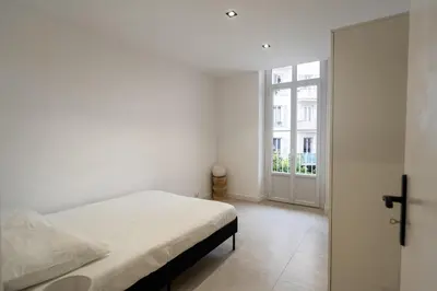 a white bedroom with a bed and a window at Bright apartment in Nice in Nice