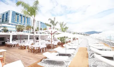 a restaurant with white tables and chairs and palm trees at Duplex studio 50 mètres de la plage in Nice