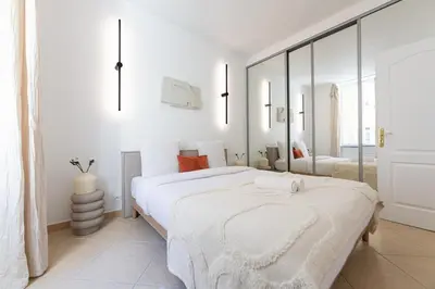 a white bedroom with a large bed and a mirror at Coup de cœur 3 couchages Quartier du Port in Nice