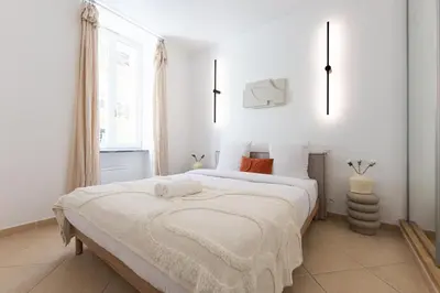 a white bedroom with a large bed with white sheets at Coup de cœur 3 couchages Quartier du Port in Nice