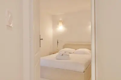 a bedroom with a bed with white sheets and a mirror at Magnifique appartement rénové au port de Nice in Nice