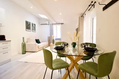 a dining room with a glass table and green chairs at Magnifique appartement rénové au port de Nice in Nice