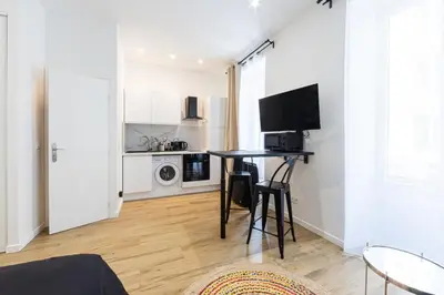 a living room with a table and a kitchen at Studio Cosy et confortable hyper centre in Nice
