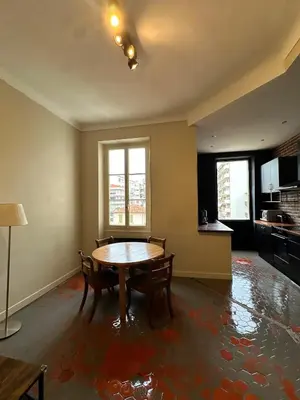 a living room with a table and a kitchen at Renovated 2-room apartment Sleeps 4 Tram and shops nearby in Nice