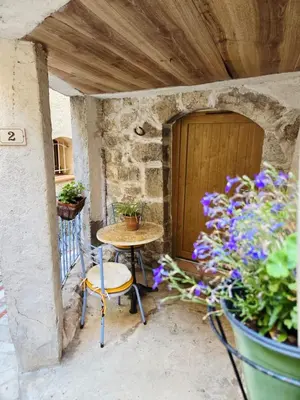a patio with a table and chairs and a door at La grotte in Aspremont
