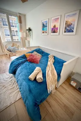 a bed with a blue blanket in a bedroom at Charmant studio avec terrasse pour amoureux in Nice