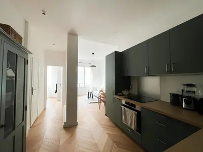 a kitchen with black cabinets and a wooden floor at Nice Boheme in Nice