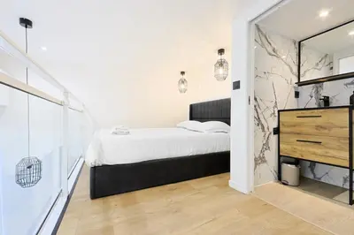 a white bedroom with a bed and a mirror at Duplex moderne climatisé Carré d'or in Nice