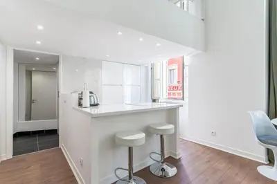 a white kitchen with a counter and stools at La Perle de Masséna in Nice