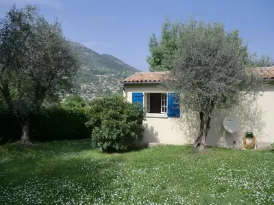a white house with a blue window and two trees at Nice Petite maison mitoyenne avec piscine in La Gaude