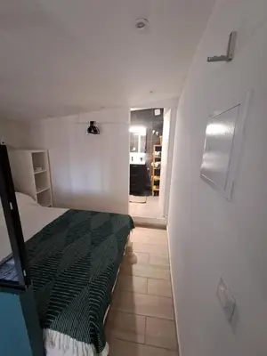 a small bedroom with a bed and a hallway at Studio dans le vert in Nice