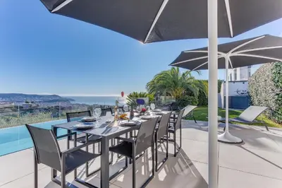 a table with chairs and an umbrella on a patio at Villa Alba VI4498 by Riviera Holiday Homes in Nice