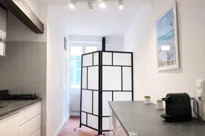 a kitchen with white walls and a black counter top at Charme du Vieux-Nice - cocon lumineux à 100 m de la mer in Nice