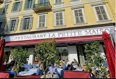 a restaurant with people sitting at tables in front of a building at Vieux Nice bord de mer in Nice
