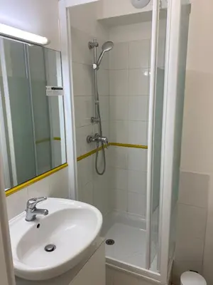 a white bathroom with a sink and a shower at Palais Des Domes Adagio Aparthotel in Nice