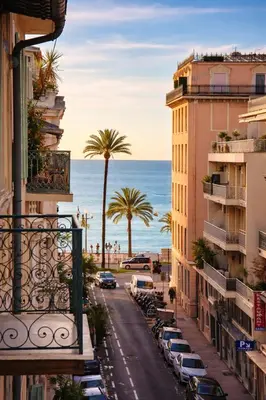 a city street with buildings and palm trees and the ocean at Azur Carré d'or Duplex 6 pers 2 min de la mer in Nice