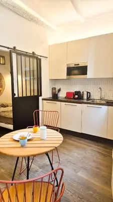 a kitchen with a table and chairs in a room at Grand studio cosy au cœur du Vieux-Nice in Nice