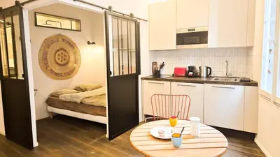 a small kitchen with a table and a room with a bed at Grand studio cosy au cœur du Vieux-Nice in Nice