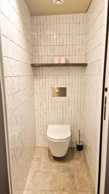 a bathroom with a toilet in a white tiled wall at Grand studio cosy au cœur du Vieux-Nice in Nice