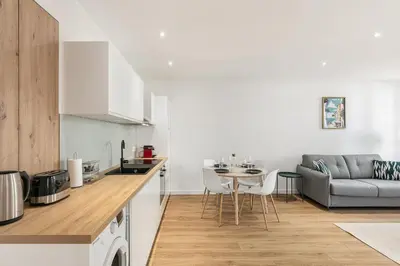 a kitchen and living room with a table and a couch at Élégant 2 pièces Niçois - Carré d'Or - Centre Ville - Mer à 2 min in Nice
