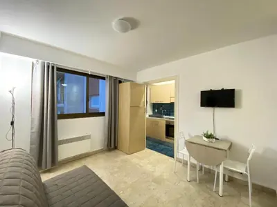 a living room with a table and a kitchen at Emanuela in Nice