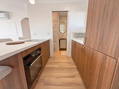 a kitchen with wooden cabinets and a wooden floor at Nice Ouest Chambres Privees Modernes TV Wifi Bureau in Nice