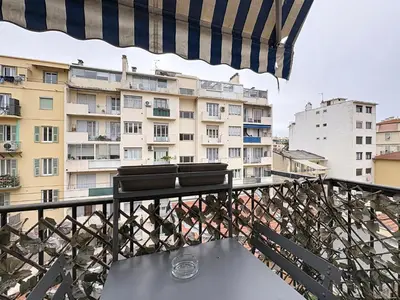 a balcony with two chairs and an umbrella at Spacieux 3p Nice Riquier terrasse clim parking in Nice