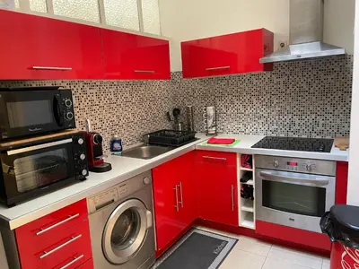 a kitchen with red cabinets and a sink and a microwave at One-Bedroom Apartment near Promenade des Anglais in Nice
