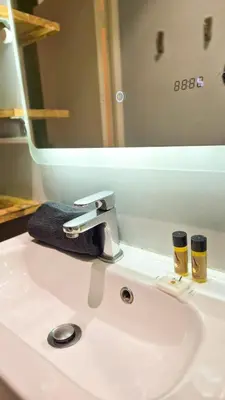 a bathroom sink with a faucet and two cups on it at Joli T3 moderne avec terrasse & climatisation in Nice