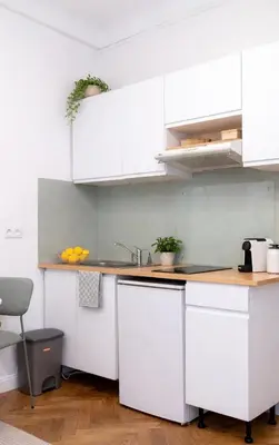 a kitchen with white cabinets and a table and a chair at Appartement en plein centre-ville in Nice