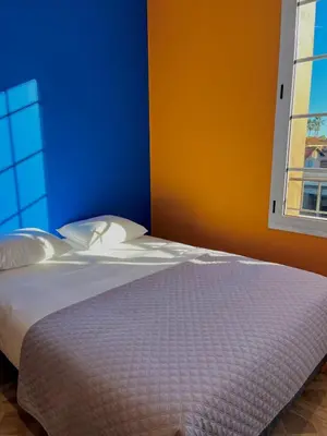 a bedroom with a bed with a blue and orange wall at Oiseau du paradis studio central pour 4 personnes in Cagnes-sur-Mer
