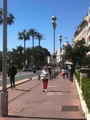 a young girl walking down a sidewalk on a city street at Super flat in Carré d'Or - 1 minute from the sea in Nice